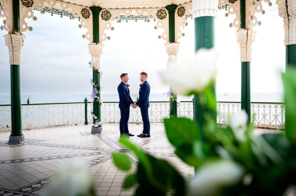 Loving grooms holding hands at Brighton Bandstand